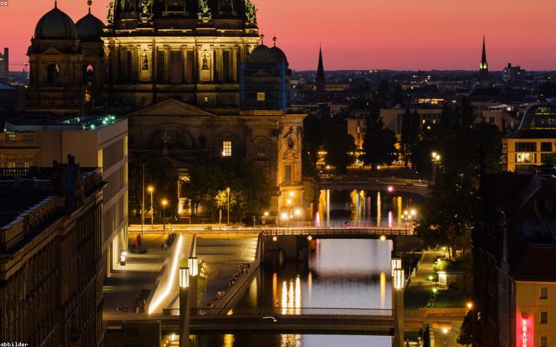 A person sipping water from an elegant infused water bottle, maybe a jug of cucumber-mint water, looking refreshed against a subtle backdrop of a cityscape at night.