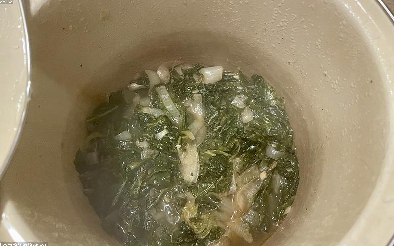 Biryani layering in a large pot, showing the vibrant colors of rice, mutton gravy, herbs, and fried onions.