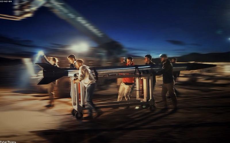 A smiling group of friends holding steaming chai cups, posing happily in front of the 