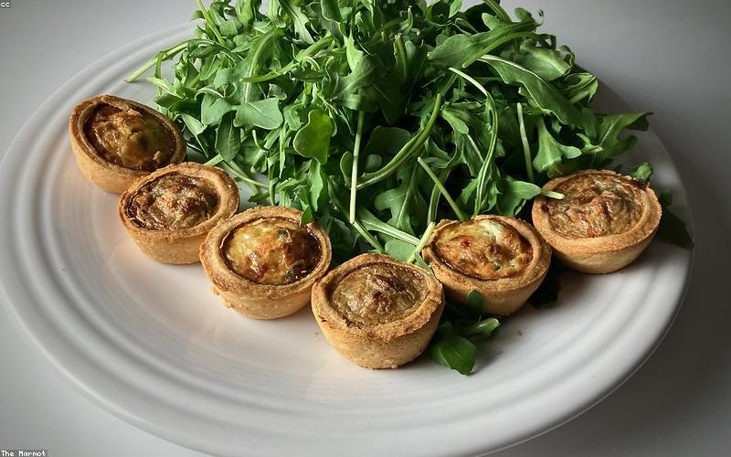 A refreshing glass of chilled water with lemon slices, next to a bowl of colorful fruit salad.