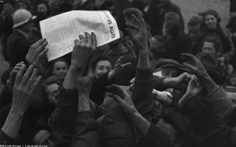 A bustling Pakistani street scene with people looking at their phones or newspapers