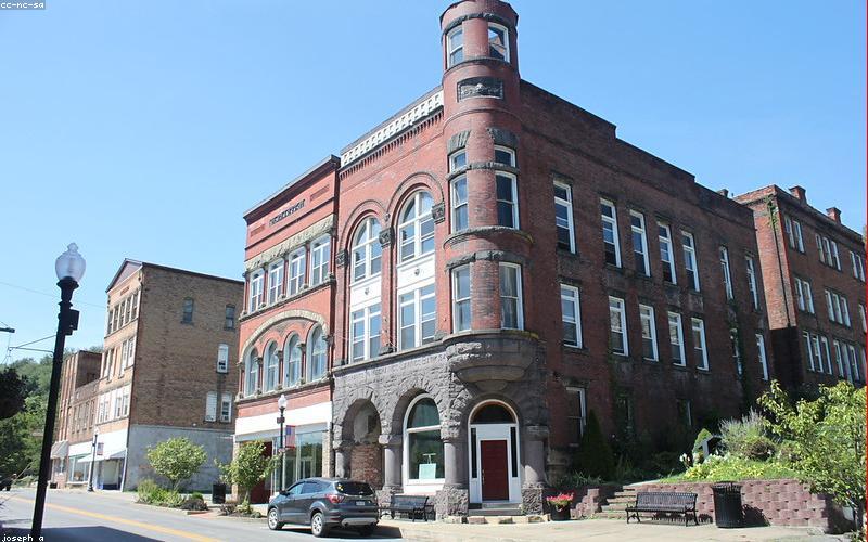 A modern Pakistani family smiling proudly next to their home solar power system, featuring a sleek lithium battery bank