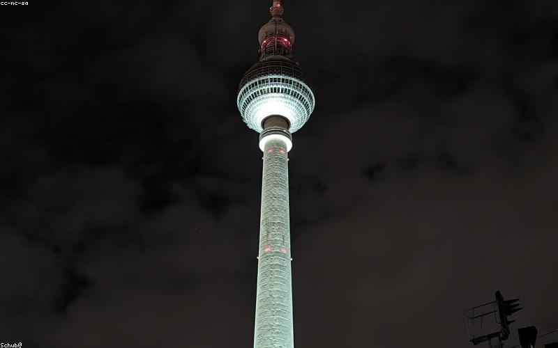 A person hiking with a backpack that has a foldable solar panel attached, charging a smartphone.