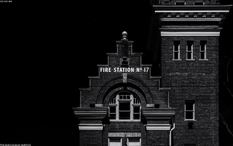 A stack of Pakistani rupee notes next to a fuel pump nozzle, with graphs in the background