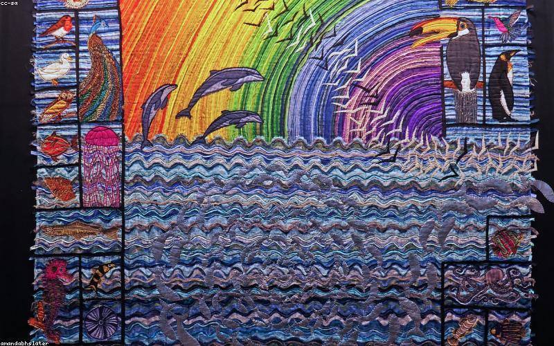 A Pakistani family smiling under a solar-powered fan on a rooftop with solar panels