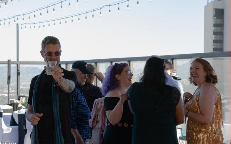 A person smiling while pointing to a solar panel installation on a rooftop.